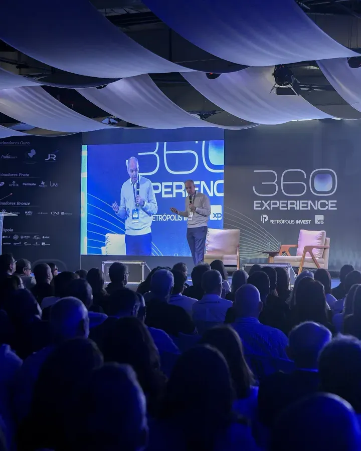 Auditório lotado na 1ª edição, com o palco iluminado e o painel do 360 Experience ao fundo